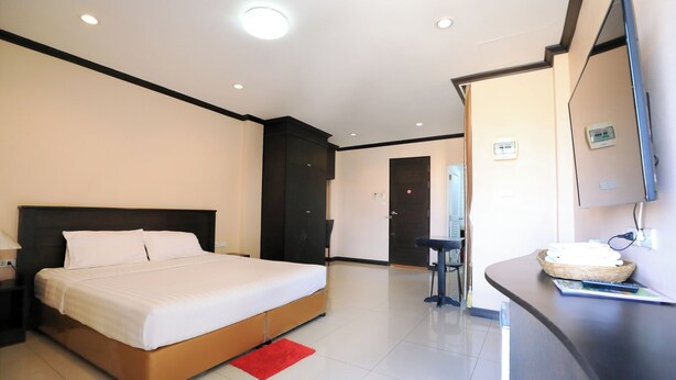 A modern hotel room with a large bed, a desk with a computer, and a flat-screen TV.