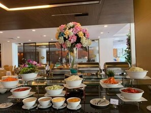 Montaje de bufé con diversas opciones de comida y un centro de mesa floral.