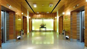 Un moderno hall de hotel con paneles de madera, una decoración floral central y un suelo pulido.