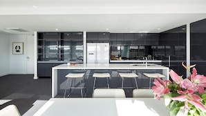 A modern kitchen with a central island, bar stools, and a dining table. - 381 Cremorne (Cremorne)