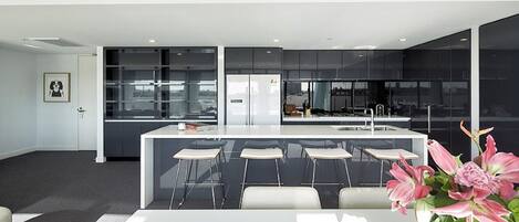 Una cocina moderna con una isla central, taburetes de bar y una mesa de comedor.