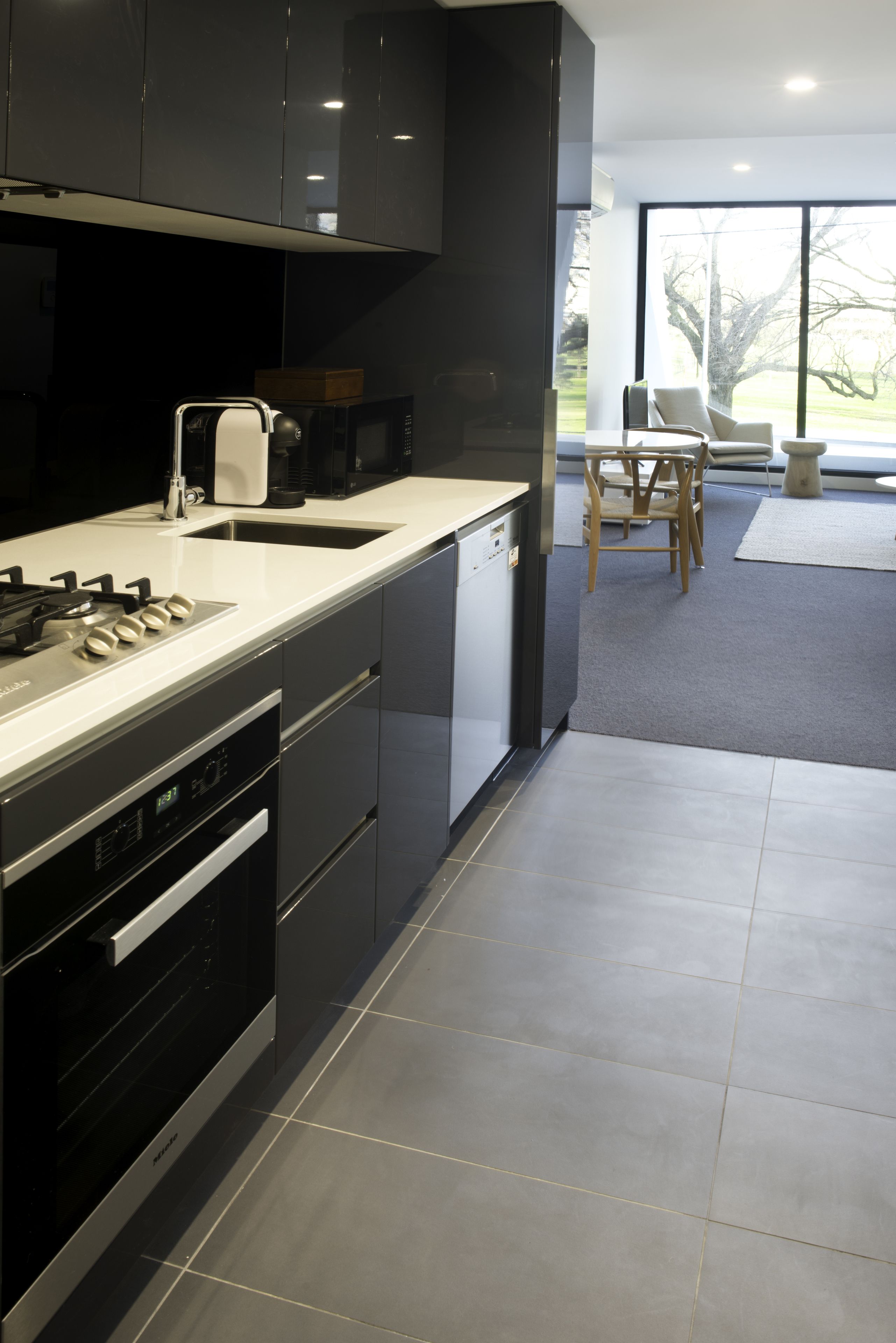 Una cucina moderna con mobili scuri, piano cottura in acciaio inossidabile e lavastoviglie integrata.