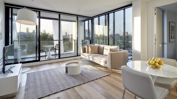 A modern living room with a large window, a sofa, a dining table with fruit, and a round coffee table. - 381 Cremorne (Cremorne)