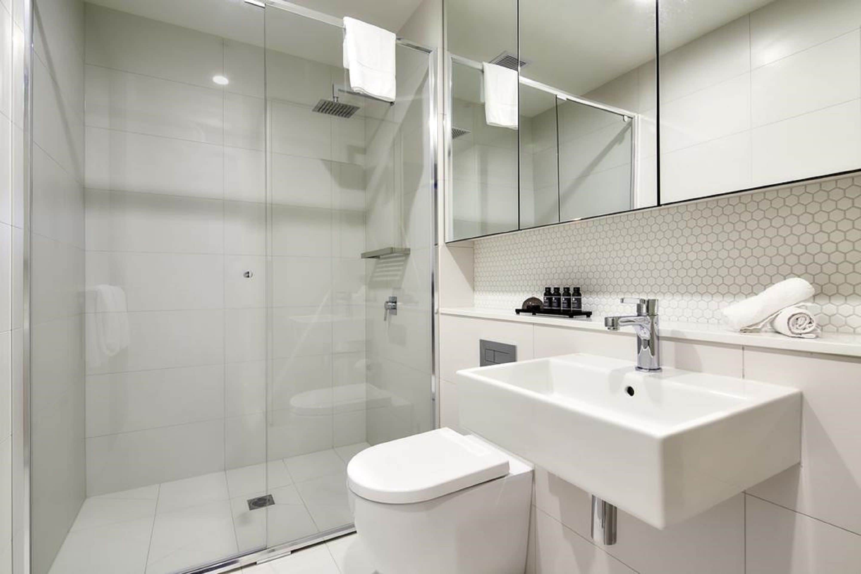 A modern bathroom with a glass-enclosed shower, a white sink, and a toilet.