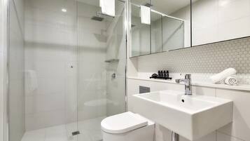 A modern bathroom with a glass-enclosed shower, a white sink, and a toilet.