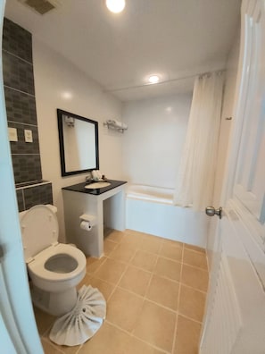 A bathroom with a toilet, sink, mirror, and bathtub. - Ampo Residence (Uthai)