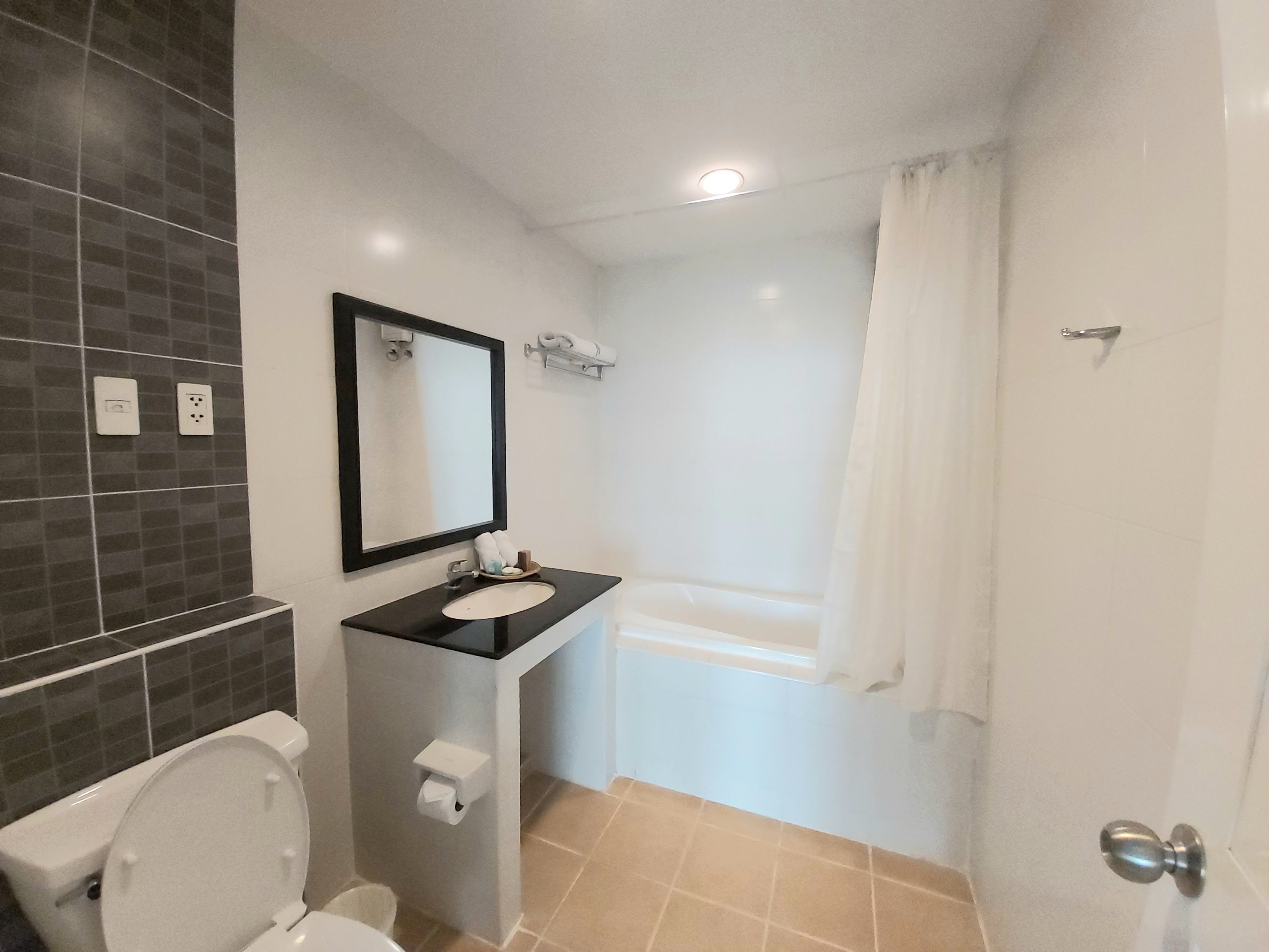 A bathroom with a toilet, sink, mirror, and bathtub.