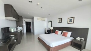 Ein Hotelzimmer mit Bett, Nachttischen, einem Schreibtisch mit Computer und einer Küchenzeile.