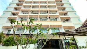 Ein mehrstöckiges Hotel mit modernem Design, das Balkone auf jeder Etage und einen überdachten Eingangsbereich bietet.