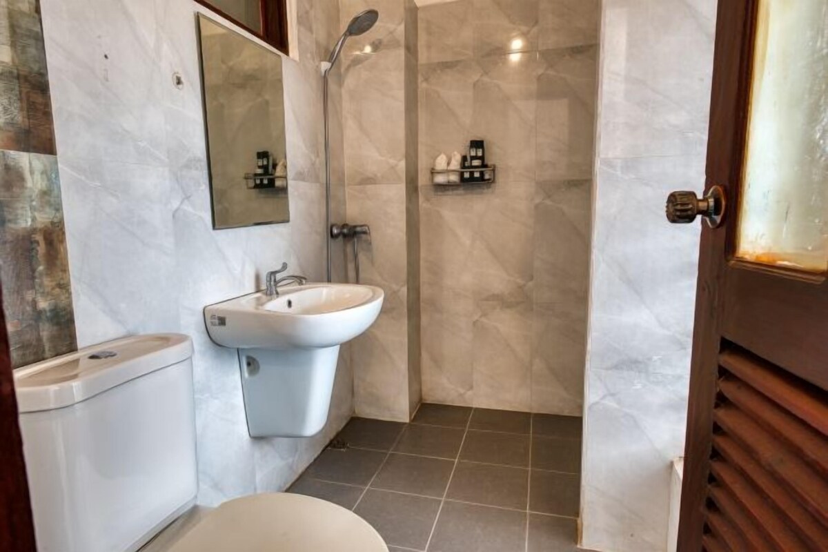 Un baño con inodoro, lavabo, espejo, ducha y un perchero para toallas.