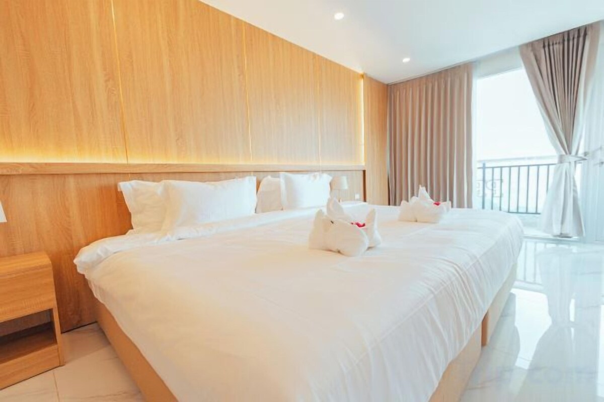 A large bed with white bedding and pillows, a wooden headboard, and a nightstand.