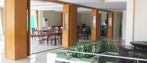 Un vestíbulo amplio con diseño moderno, que incluye una zona de estar con bancos y un pequeño jardín interior.