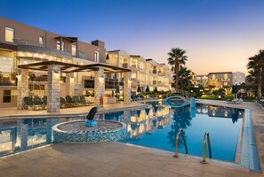 A hotel with a swimming pool, outdoor seating, and a covered area with umbrellas. - Maleme Mare Beach Resort Hotel (Platanias)