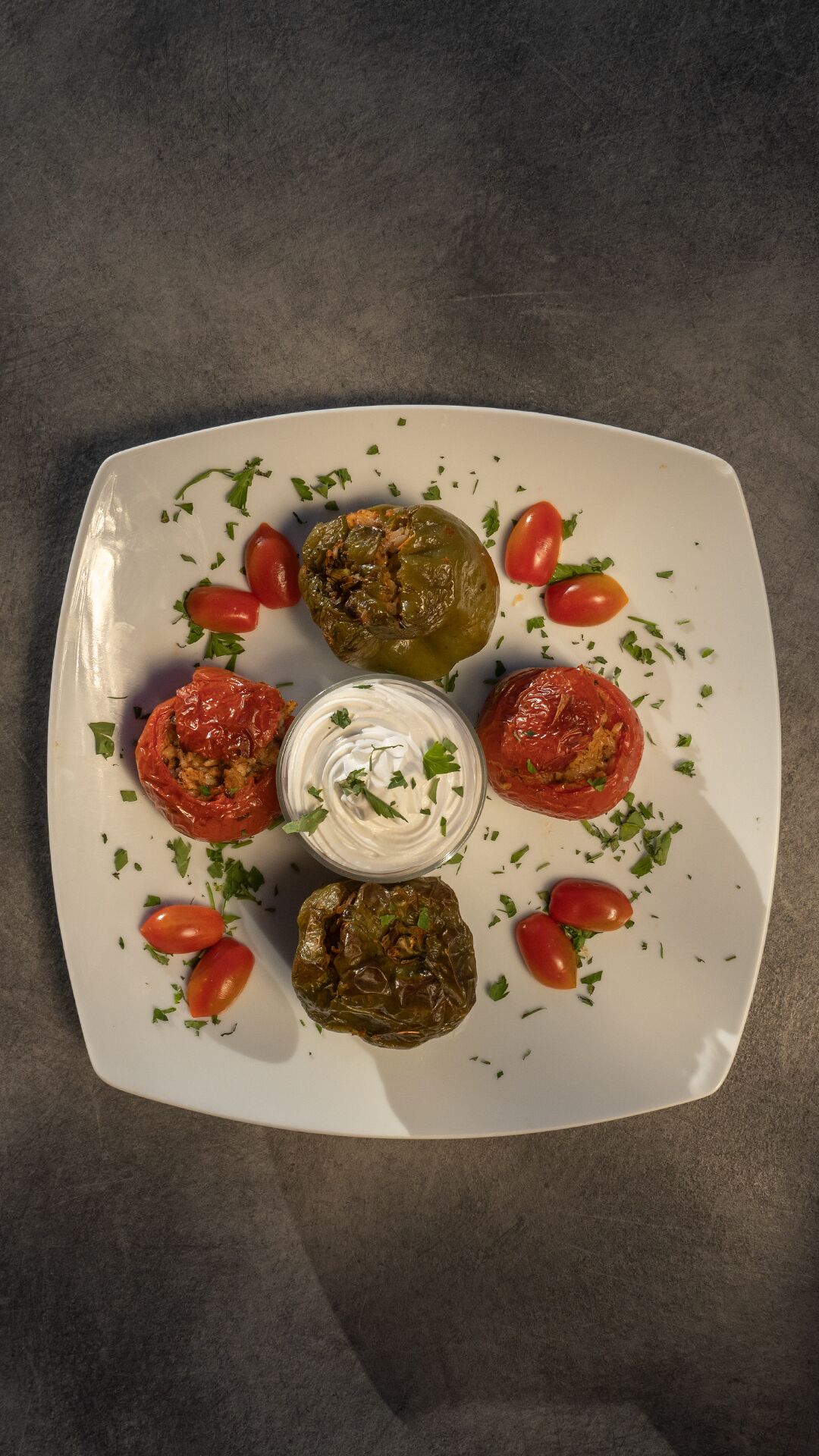 A plate with stuffed peppers and a bowl of sauce.