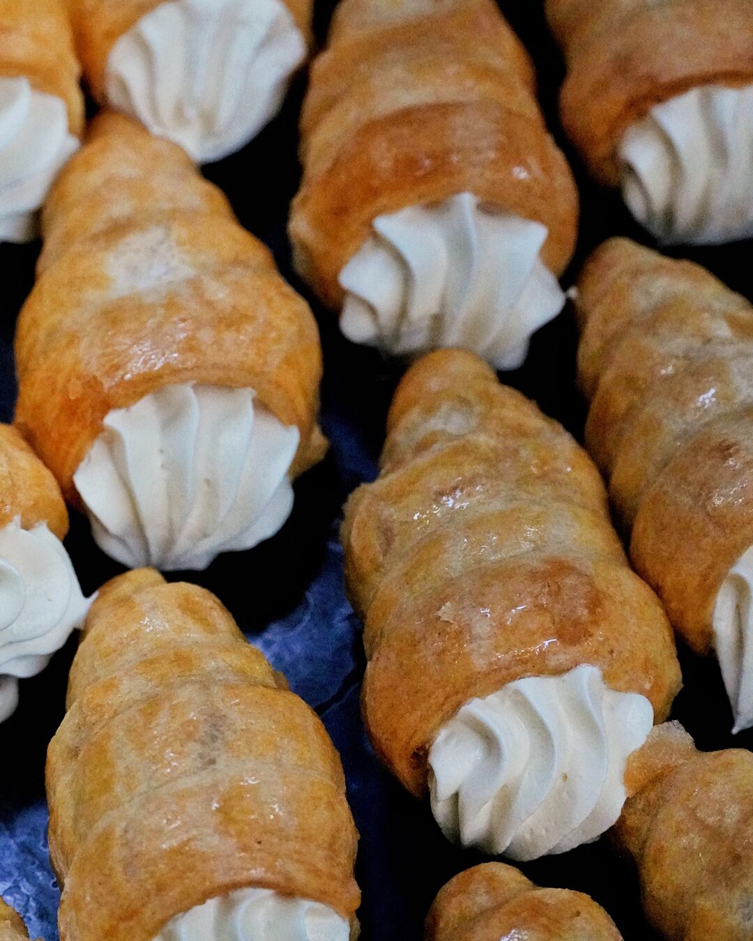 A close-up of pastries with a golden-brown crust and a white creamy filling.