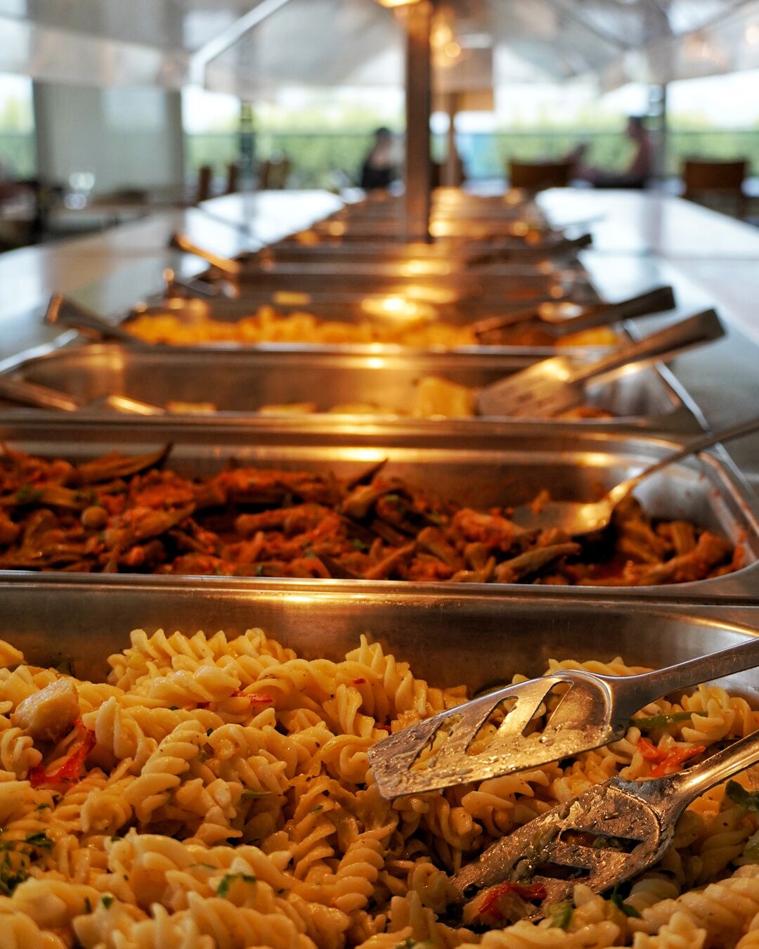 A buffet with various pasta dishes and meats.