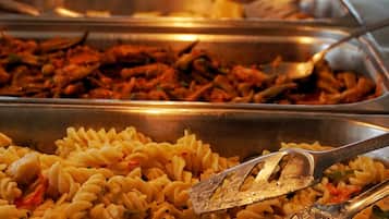 A buffet with various pasta dishes and meats.