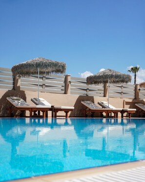 A swimming pool with lounge chairs and thatched umbrellas. - Maleme Mare Beach Resort Hotel (Platanias)