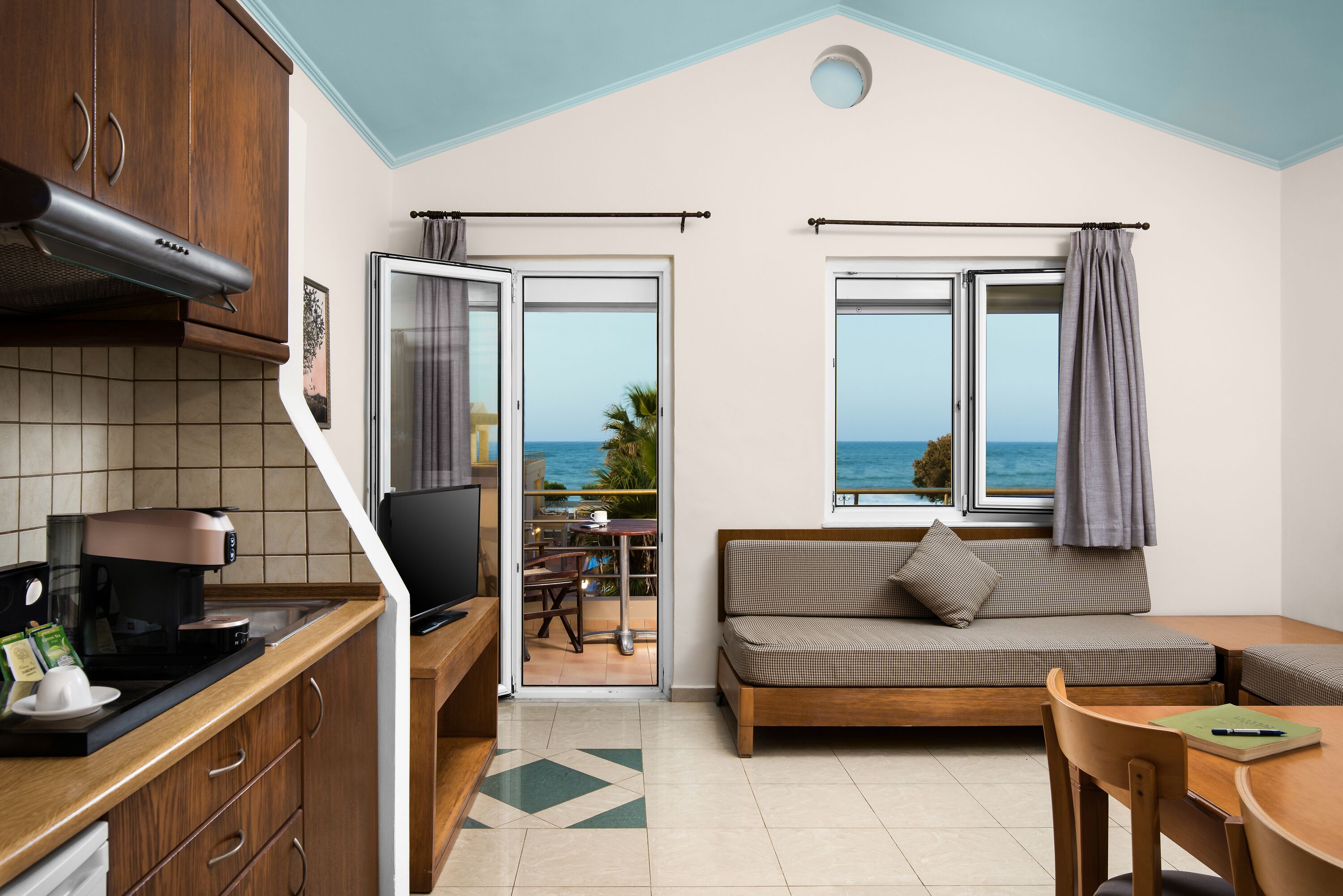 Un espacio habitable compacto con kitchenette, sofá, comedor y vistas al mar.