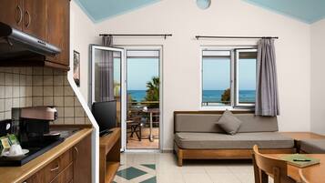 Un espacio habitable compacto con kitchenette, sofá, comedor y vistas al mar.
