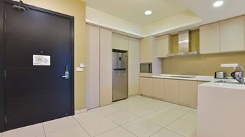 A modern kitchen with a black door, stainless steel appliances, and a white countertop.