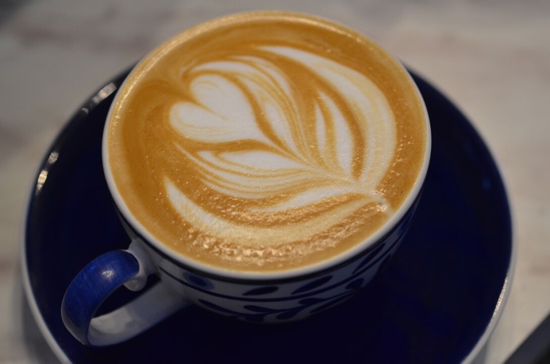 Uma chávena de café com arte de latte num pires.