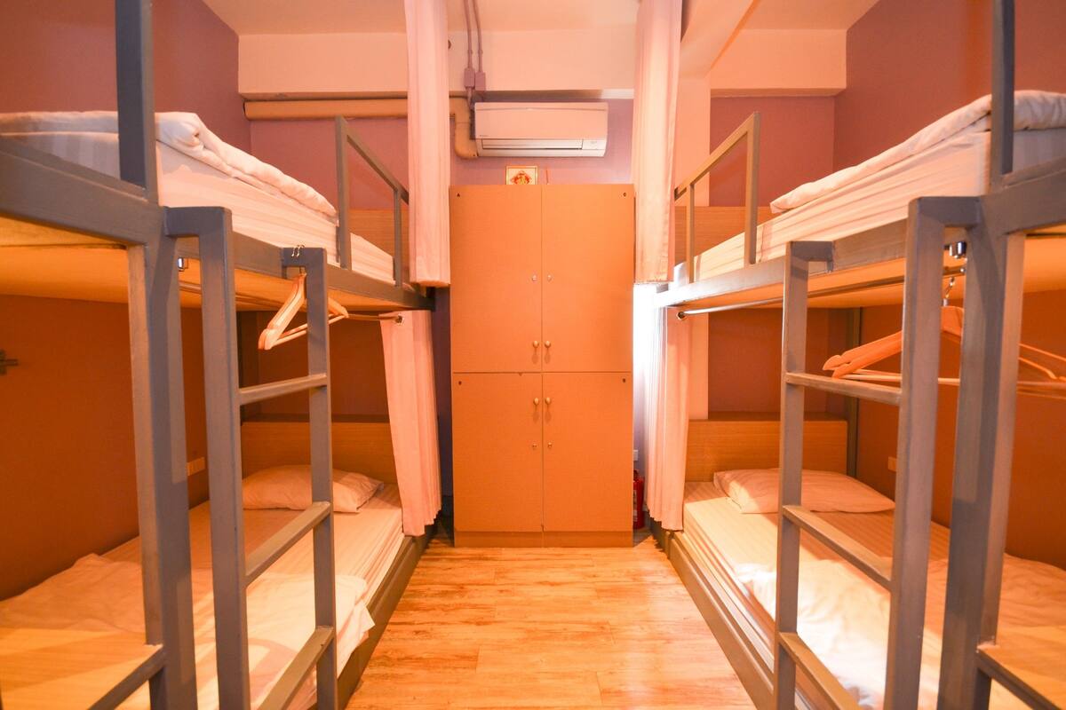 Une chambre de dortoir équipée de lits superposés, d’une armoire et d’un appareil de climatisation.