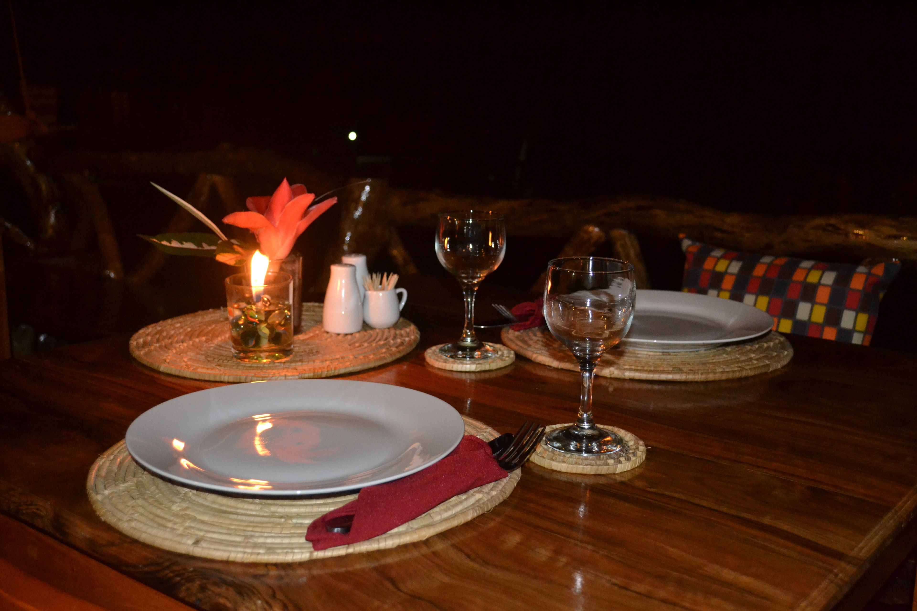 A dining table set with plates, cutlery, a candle, and a glass of water.