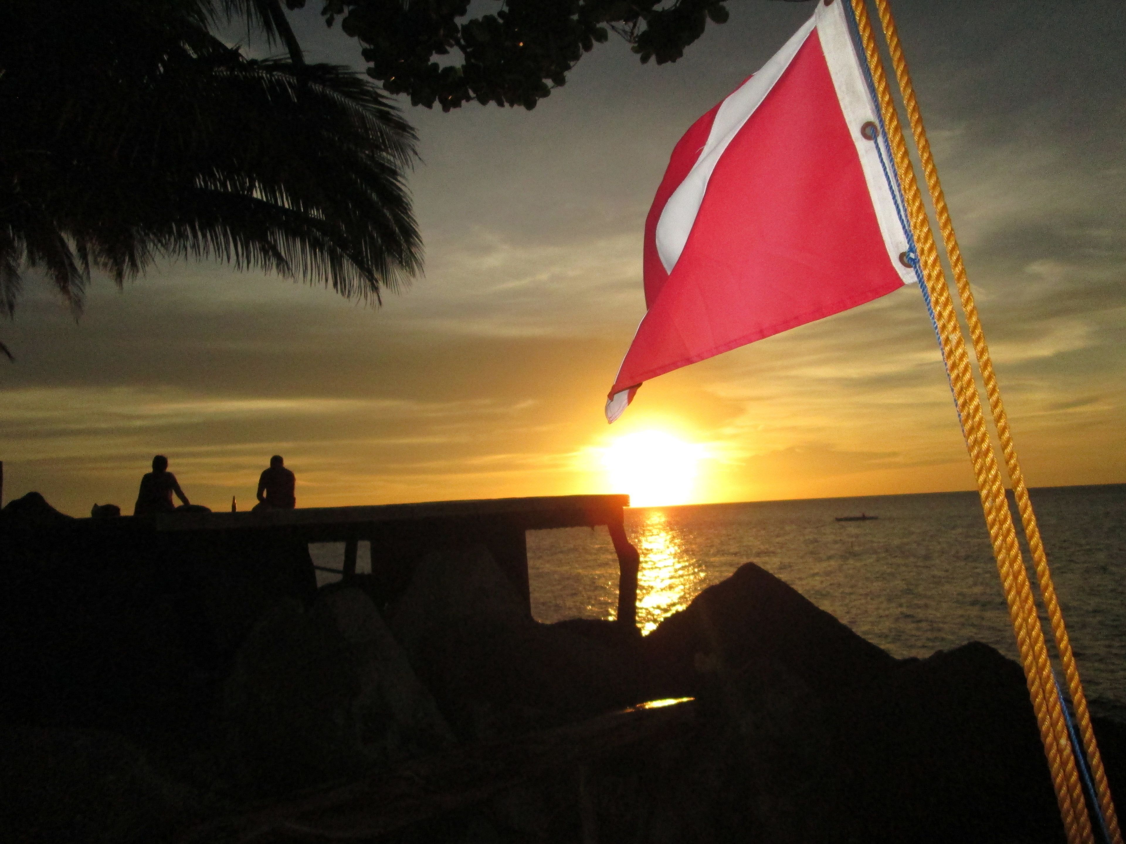 A sunset over a body of water with a flag on a pole.