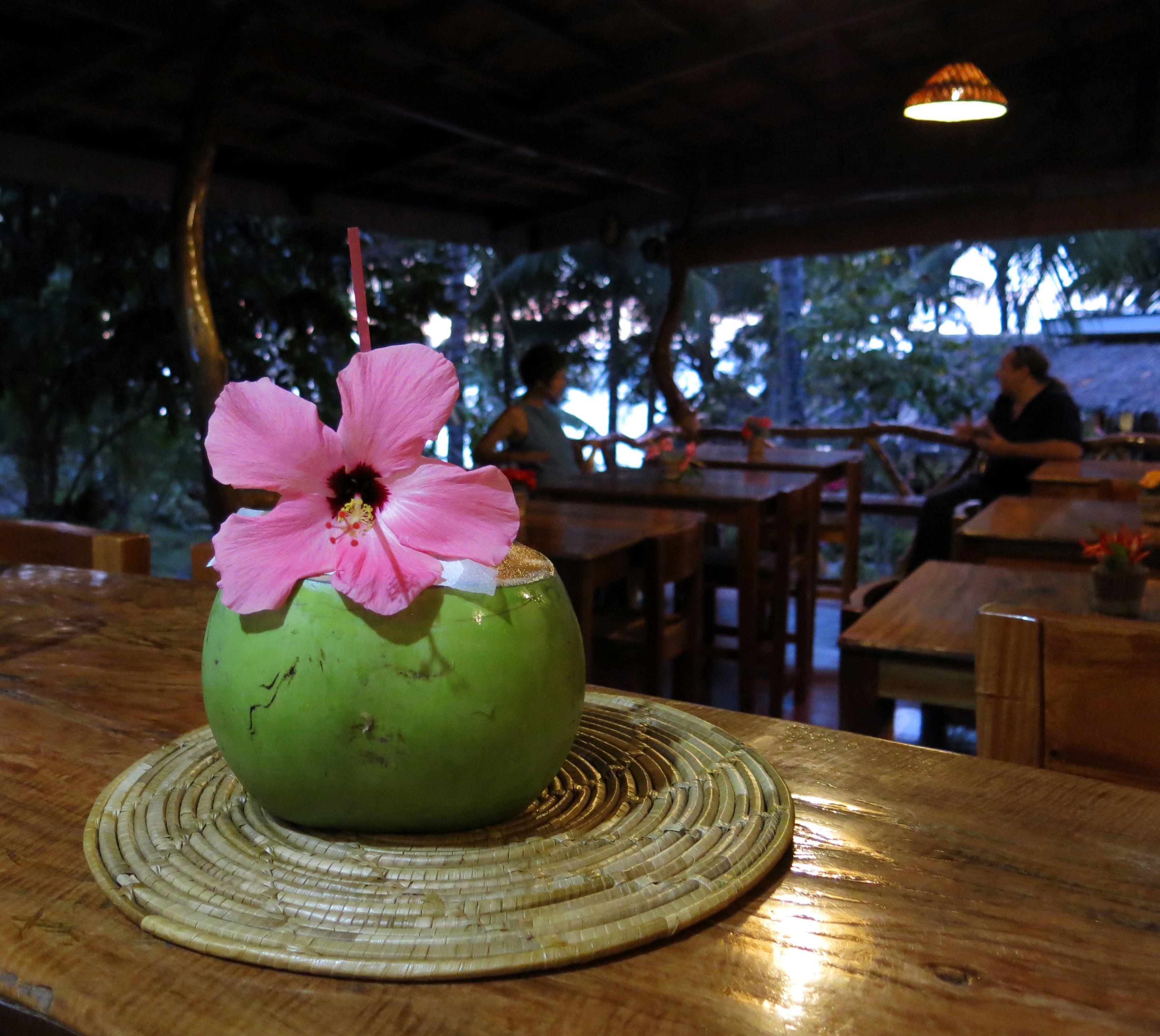 Un jarrón verde con una flor rosa sobre una mesa de madera.