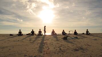 A group of people sitting on a beach at sunset.