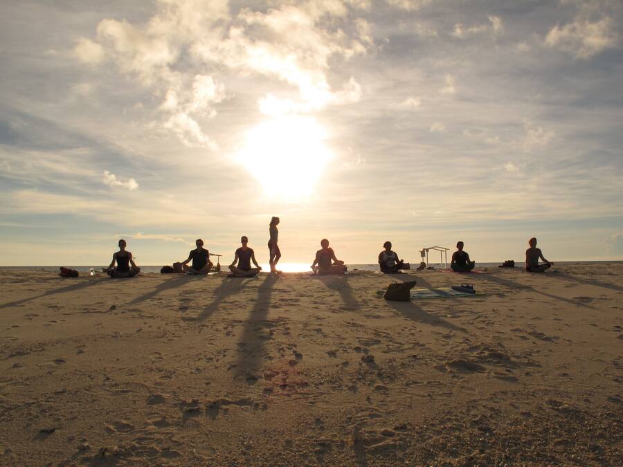 A group of people sitting on a beach at sunset.