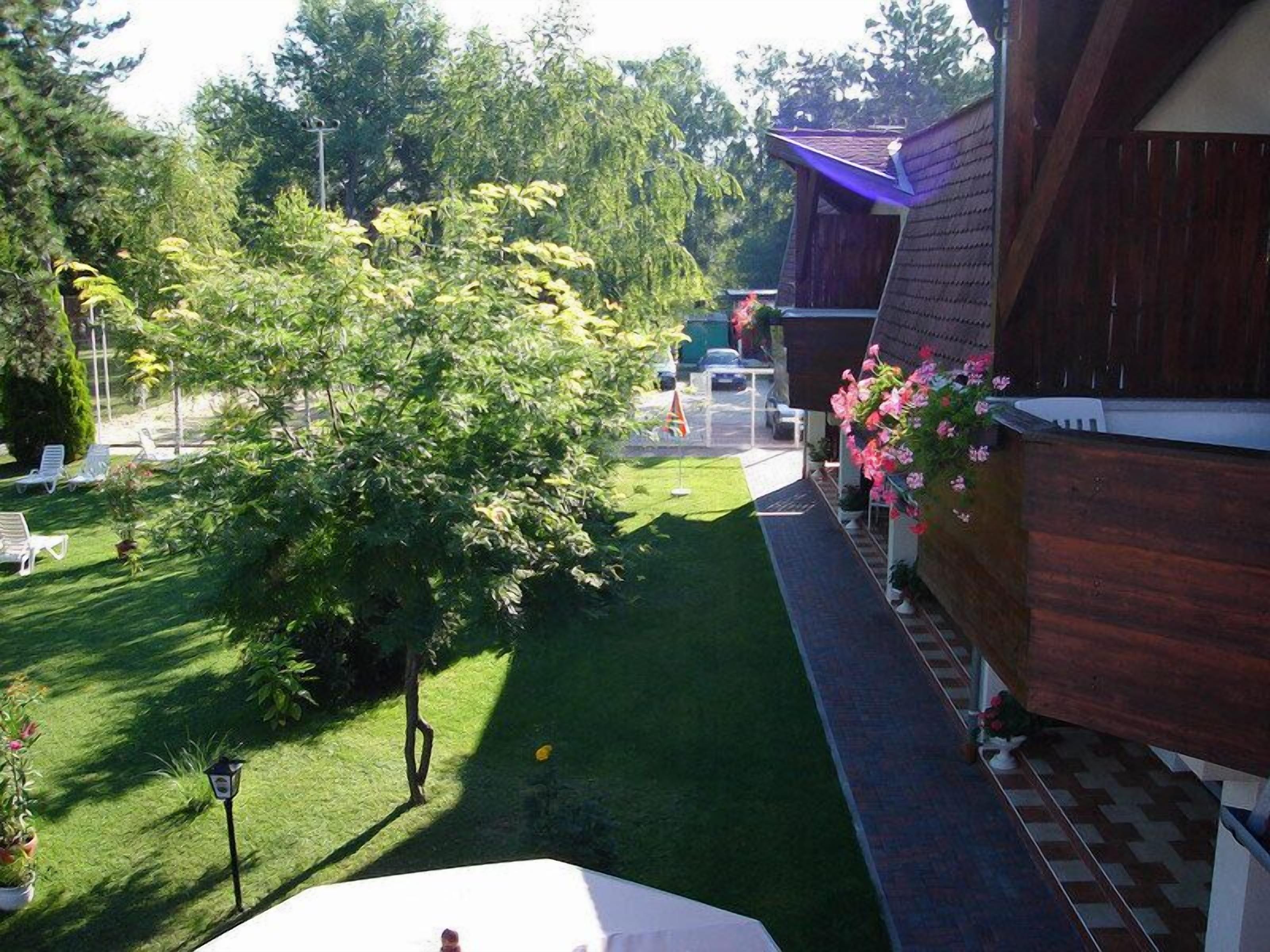 Ein gepflegter Garten mit Rasenfläche, Holzzaun und weißem Stuhl.