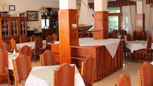 Un comedor con mesas y sillas de madera, un modelo de barco y un mueble de madera grande.