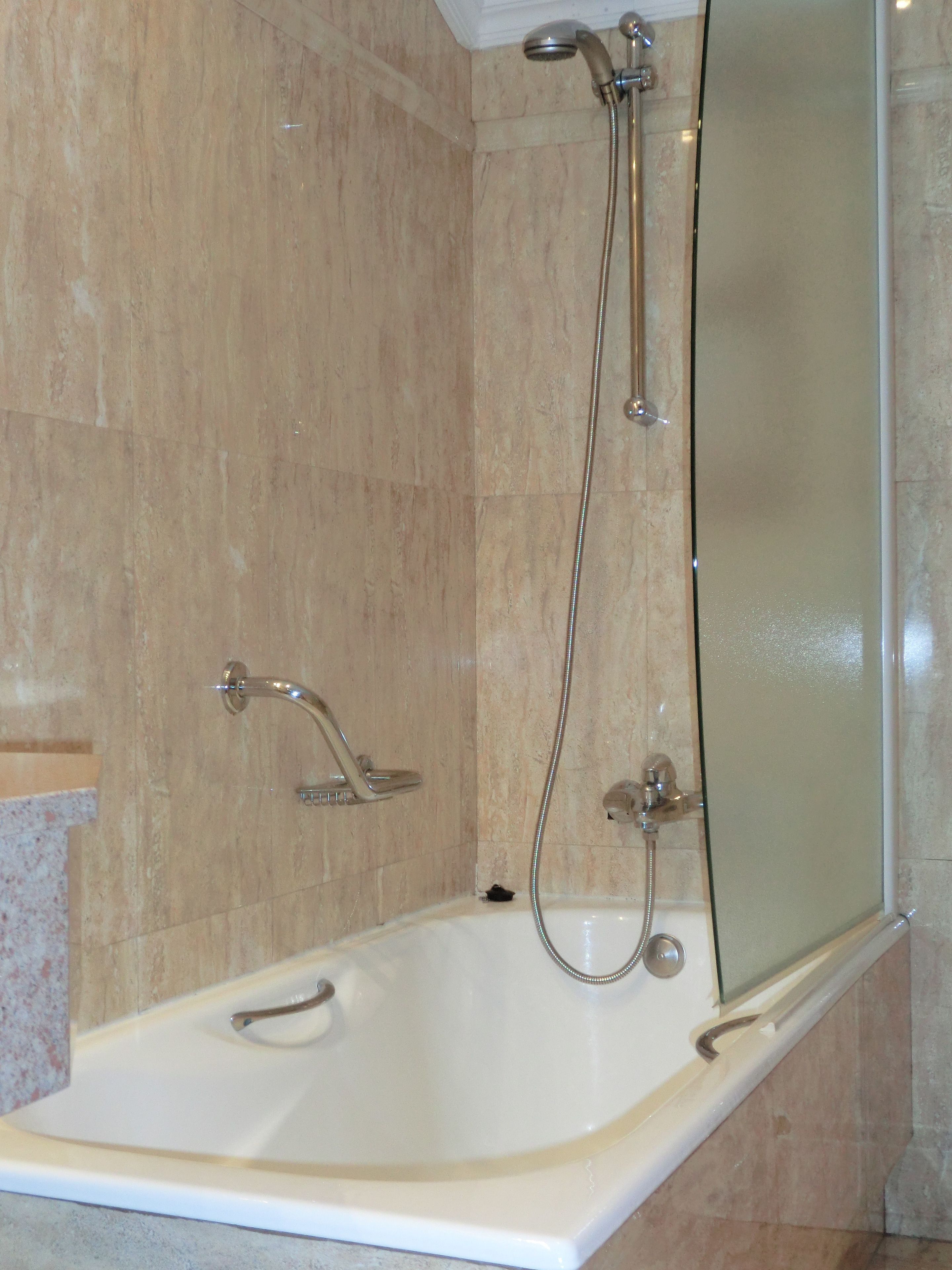 Une salle de bain moderne avec une baignoire, une cabine de douche en verre et un pommeau de douche à main.
