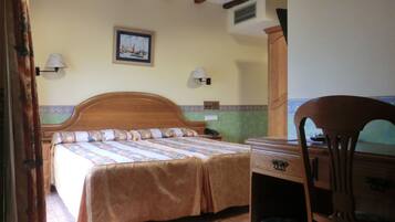 Un dormitorio con cama de madera, dos lámparas de noche, una mesita de noche, un escritorio y una silla.