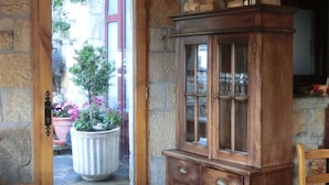 Un interior rústico con un banco de madera, una pared de piedra, un aparador de madera y una araña.