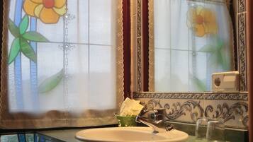 A bathroom with a sink, mirror, and decorative stained glass windows.
