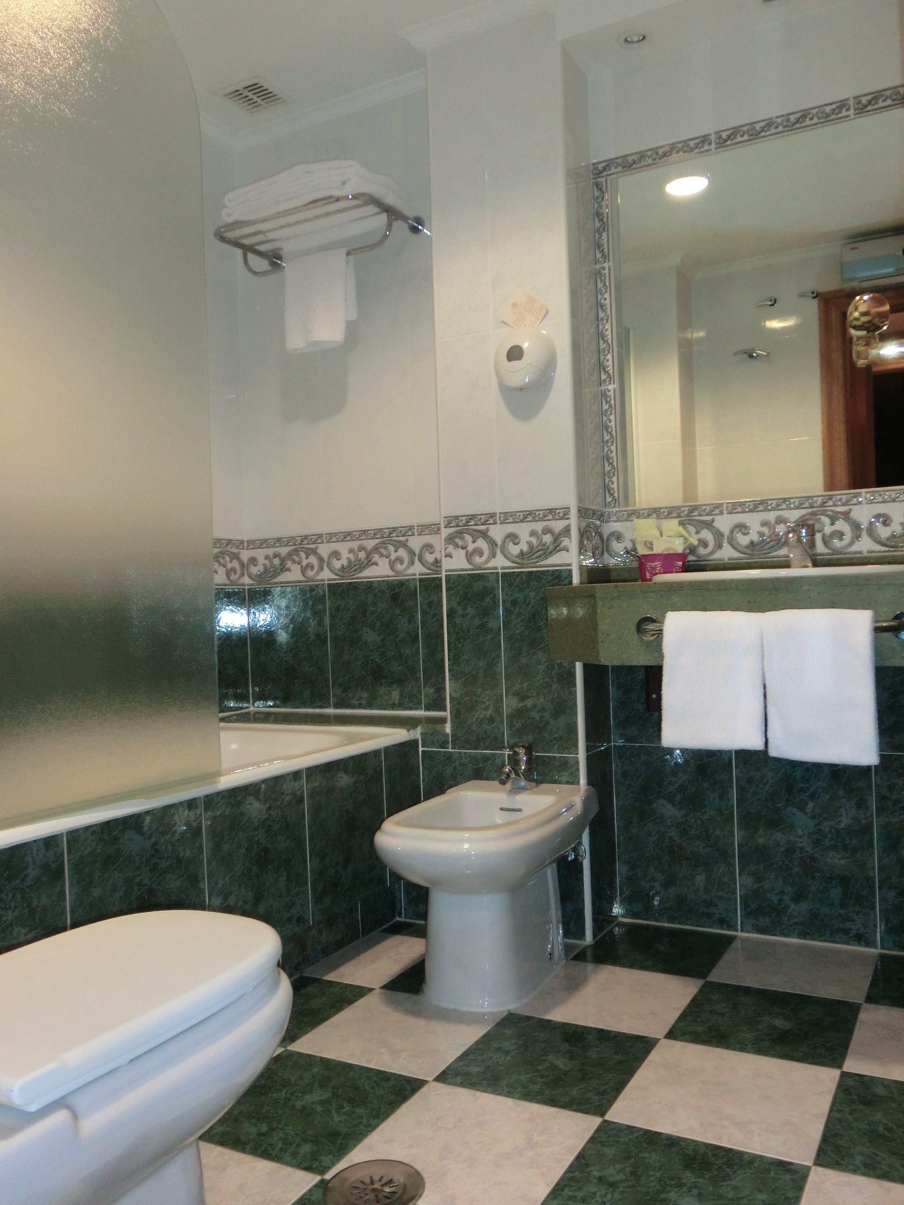 Ein Badezimmer mit Toilette, Bidet, Waschbecken und Spiegel.