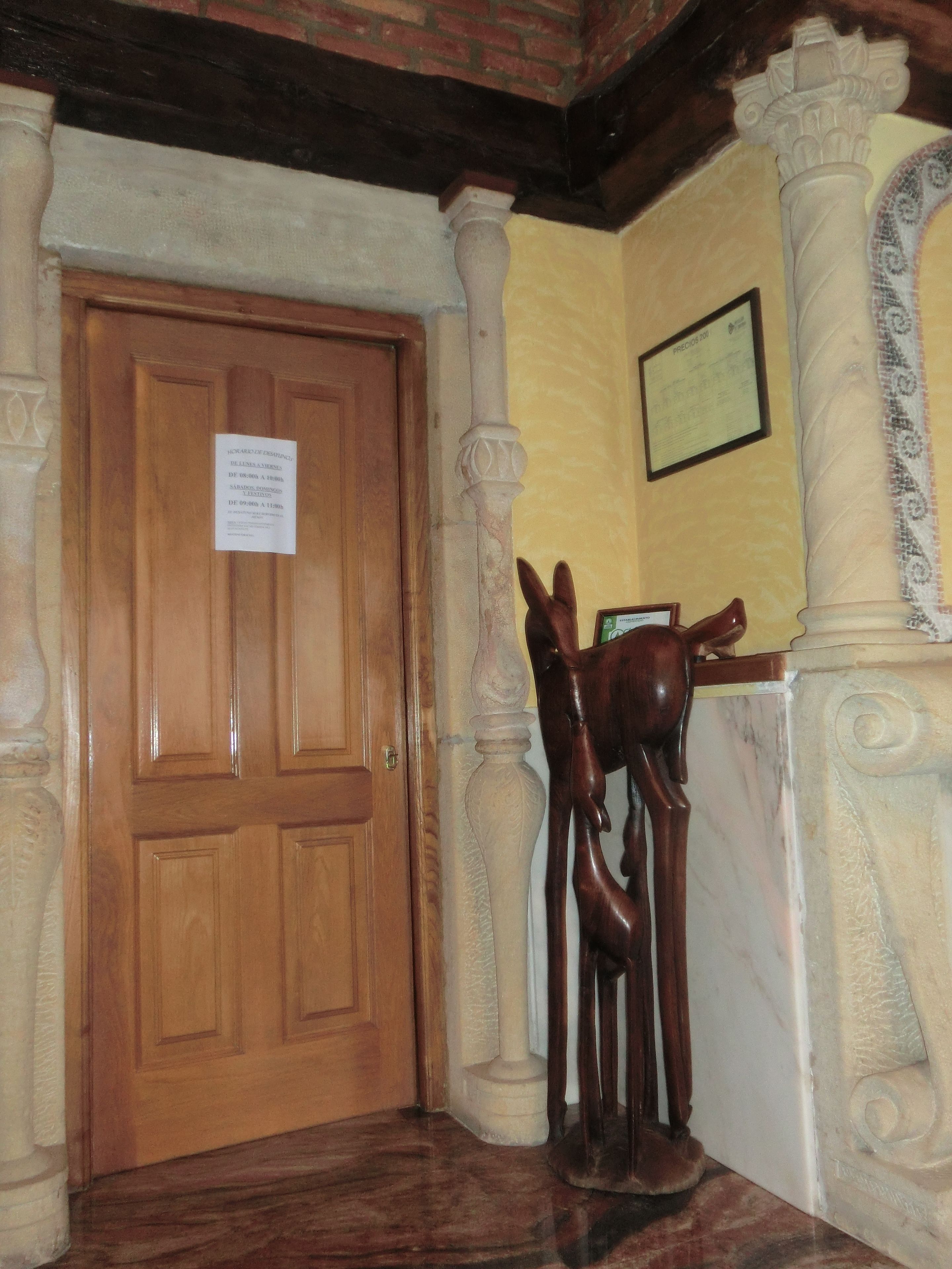 Una porta de fusta amb un senyal, una columna de marbre i una estàtua d'un cavall.