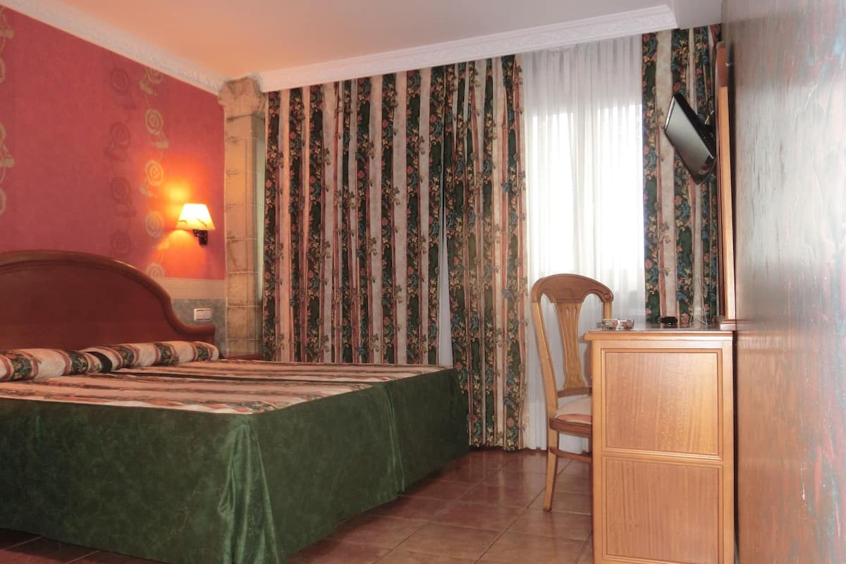 Una habitación con cama, escritorio, silla, lámpara y cortinas.