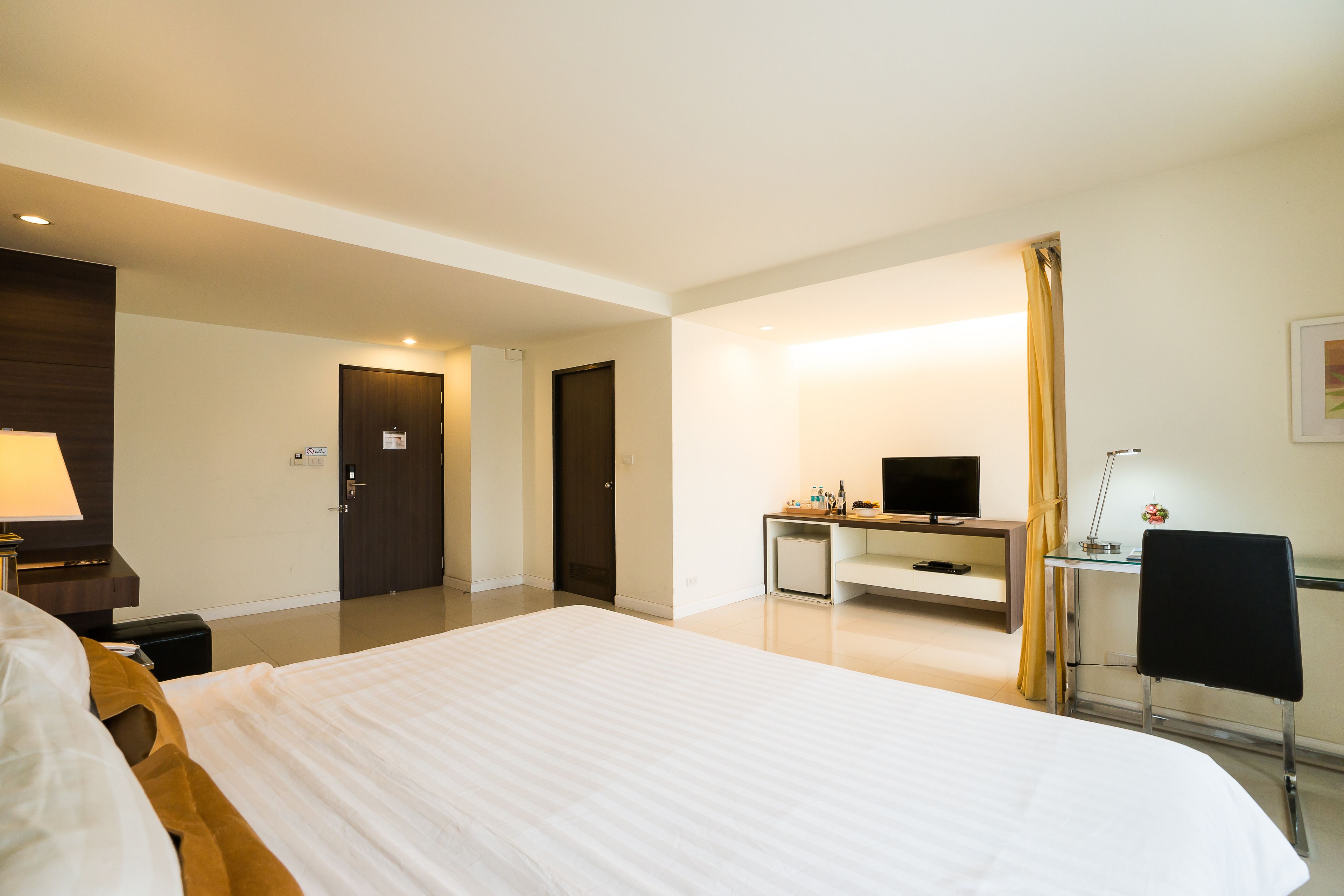 Une chambre d’hôtel avec un grand lit, un bureau avec un ordinateur, une télévision et une chaise.