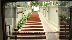 Una escalera conduce a un nivel superior, flanqueada por muros con macetas colgantes y una vista despejada del cielo.