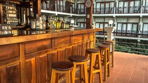 Zona de bar con taburetes de madera y diversas botellas de licor.