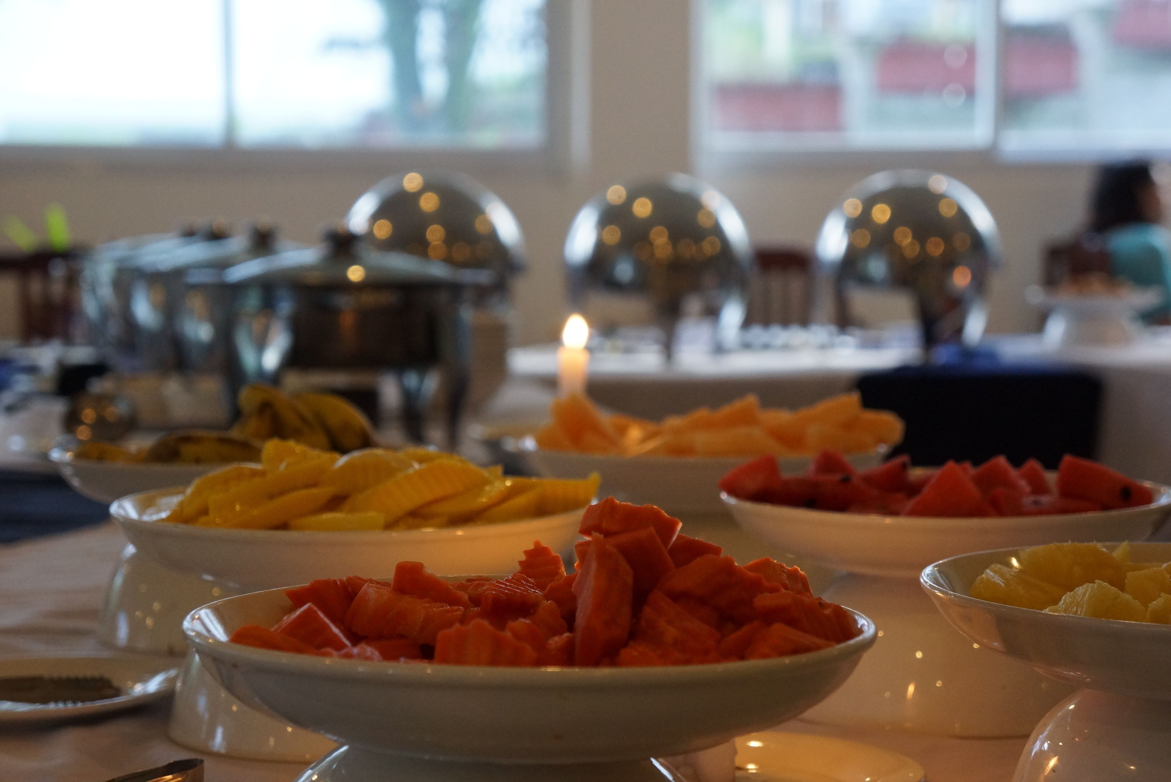 Ein Buffet mit verschiedenen Obstschalen und einer Kerze.