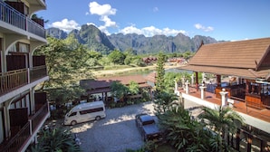 Un hotel con vista a las montañas, zona de piscina y aparcamiento con vehículos.