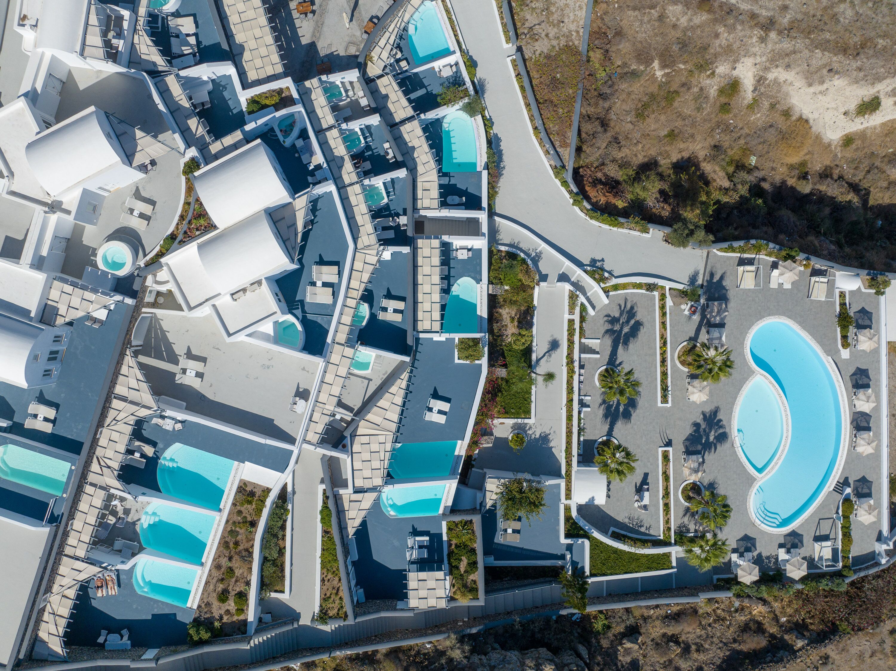 An aerial view of a resort with multiple swimming pools, lounge areas, and a large central pool.