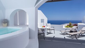 A modern outdoor terrace with a pool, white furniture, and a view of the ocean.