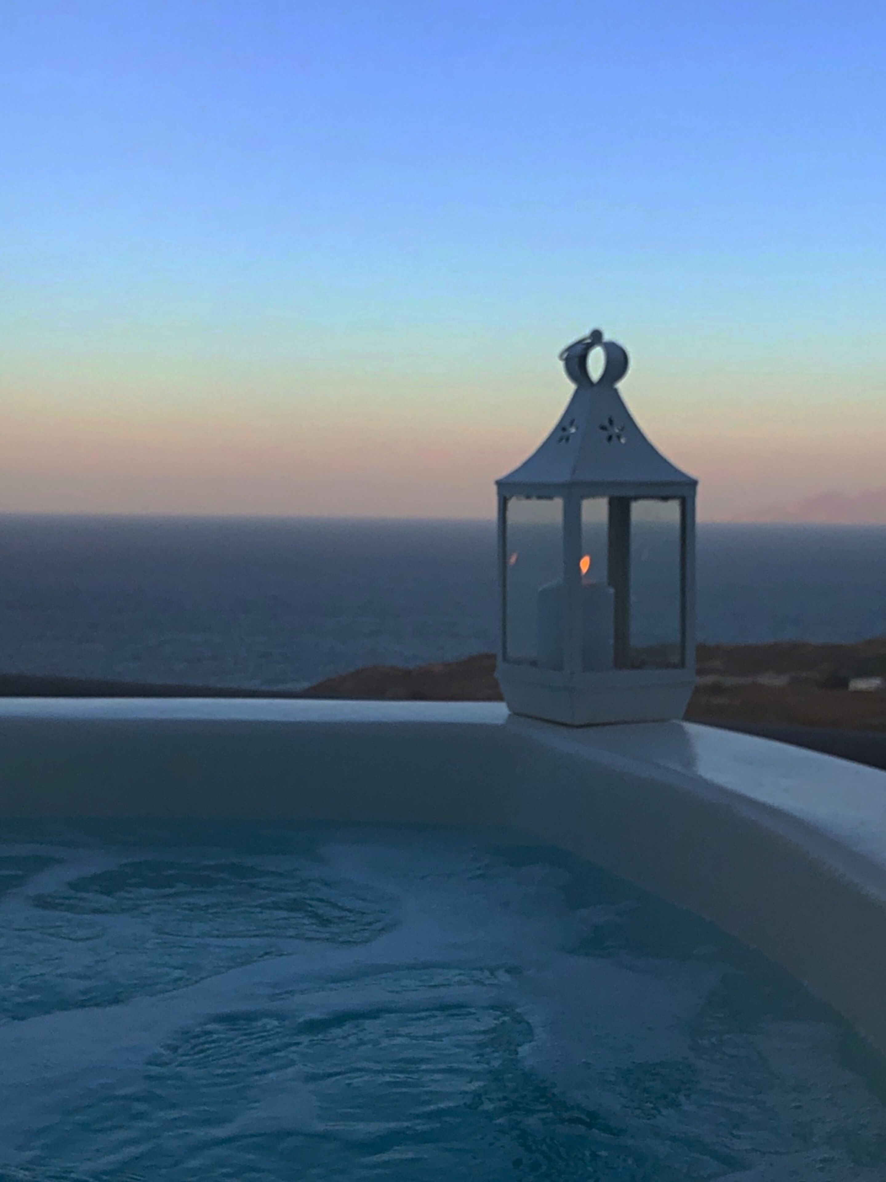A lantern on a balcony overlooking a body of water.