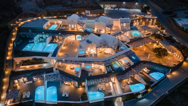 An aerial view of a resort with multiple swimming pools, interconnected buildings, and outdoor seating areas.